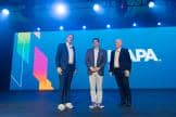 Scott O'Neil, Michael Shelton, and Jakob Wahl stand on stage together at the Leadership Breakfast, where the Best Exhibit winners were acknowledged